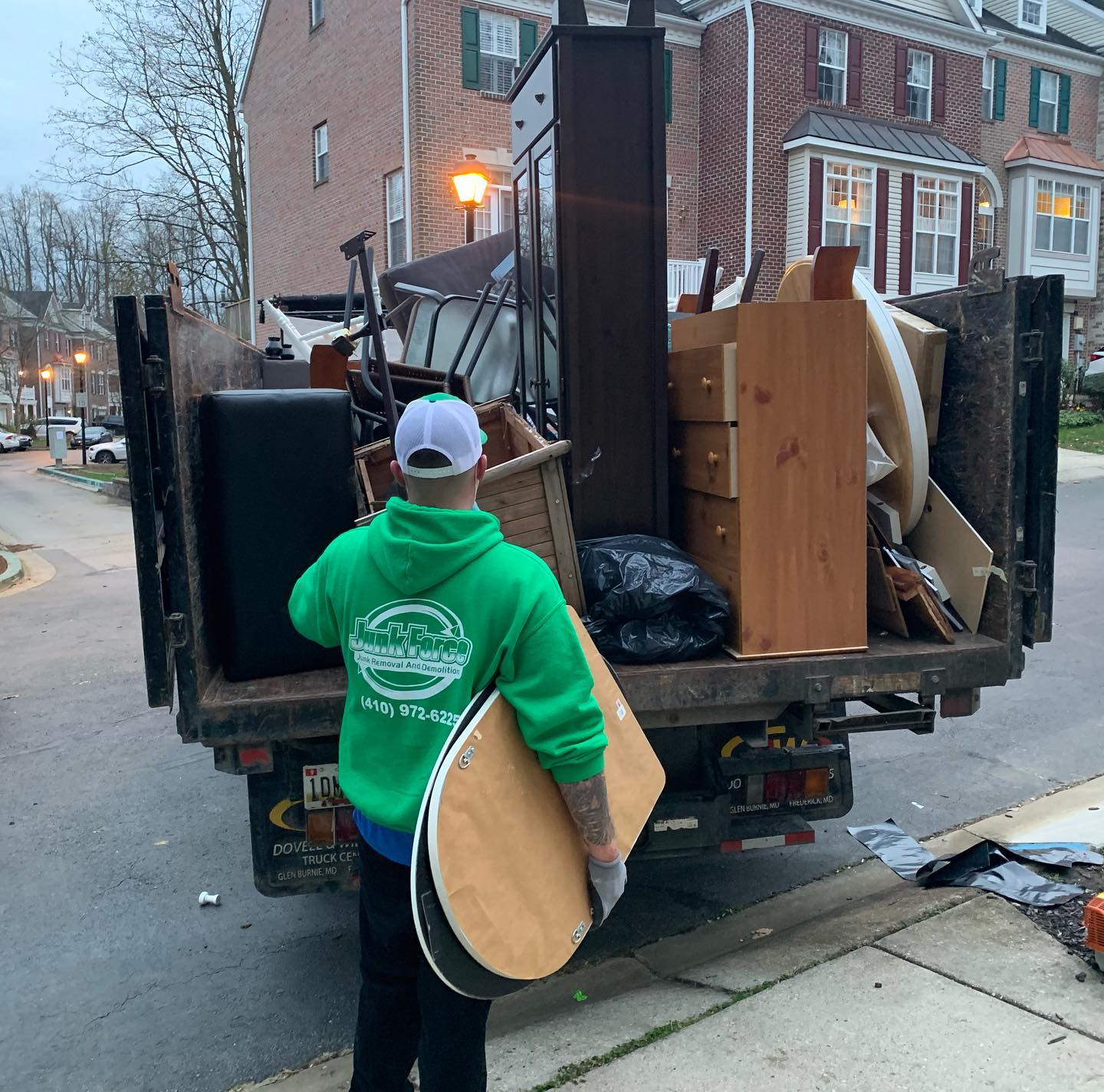 A Junk Force employee carries furniture into their junk removal truck
